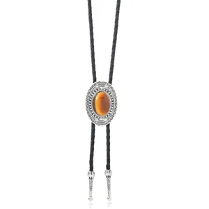 Close-up of vintage oval bolo tie pendant with ornate silver filigree and polished center stone.