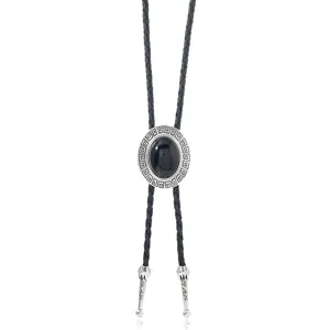 Detailed close-up of vintage oval bolo tie with black stone, braided leather cord and metal tips.
