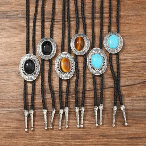 Vintage western bolo tie detail shot featuring turquoise, onyx and tiger eye stones with braided cord.