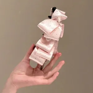Détail de pince banane nœud pois satin rose, griffe de cheveux verticale élégante.