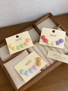 Nahaufnahme von süßen bunten Macaron runden Ohrringen ordentlich auf einem Holtablett arrangiert.