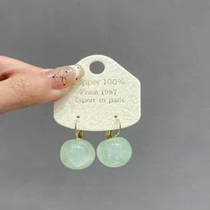 Gros plan d'élégantes boucles d'oreilles boules en marbre vert avec carte produit.