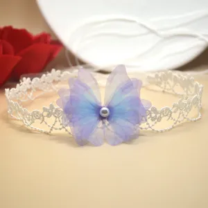 Primer plano de una gargantilla de encaje blanco con detalle de mariposa de tul morado.