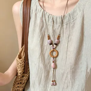 Detail view of a long retro ethnic style necklace featuring ceramic beads and wood ring.