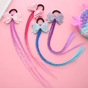 Kids colorful wig hair ties with glitter bows and braided synthetic hair extensions detail shot.