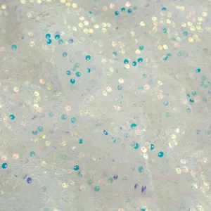 Close up detail of white iridescent sequin embroidered fabric with sparkling shiny glitter texture.