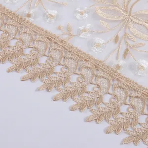 Detailed close up of gold embroidered glass yarn tablecloth lace edge design texture.