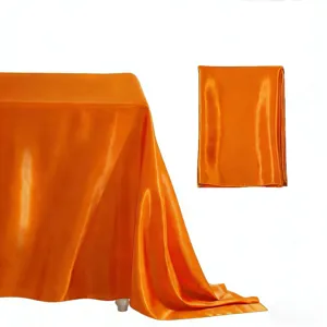Orange satin tablecloth detail view, bright silk rectangular fabric for weddings and party decor.