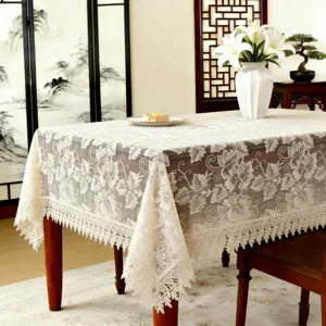 Detailed view of light brown rectangular embroidered tablecloth with lace trim for home decor.