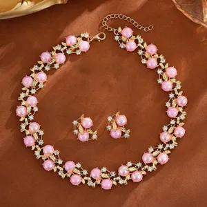 Vue détail de collier et boucles d'oreilles perles roses strass, superbes finitions.