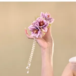 Primo piano dettagliato di molletta per capelli con fiore viola e nappina di perle, elegante.