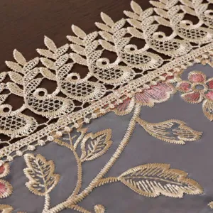 Detalle de mantel de encaje con bordado de malla fina, elegante patrón floral dorado y rosa.