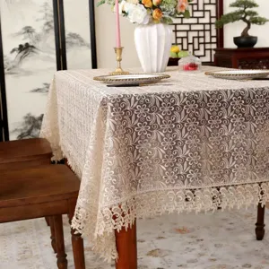Gedetailleerd overzicht van het elegante beige kanten tafelkleed met ingewikkelde bloemborduursels.