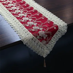 Vista detallada del elegante camino de mesa rojo con bordado dorado y finos bordes de encaje.