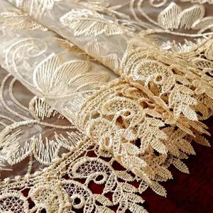 Detailed close-up of elegant beige embroidered lace table runner fabric texture.