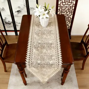 Detailansicht des eleganten beige floralen Spitzentischläufers auf dem Holztisch.