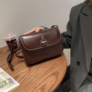 Klassische dunkelbraune Leder Umhängetasche Detail, elegante Verarbeitung mit Metallschnalle.