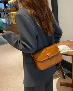 Detailaufnahme der retro braunen Ledertasche am Modell, mit klassischer Metallschließe.