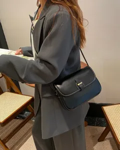 Detailansicht der eleganten schwarzen Leder-Umhängetasche vom Model, zeigt feine Nähte.