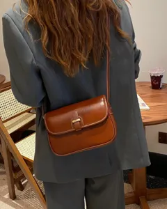 Detailaufnahme der braunen Vintage-Leder-Umhängetasche mit Metallschloss und schmalem Gurt.