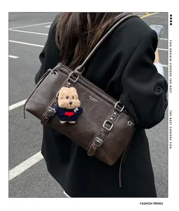 Stylish brown shoulder tote bag with buckles and cute bear charm, perfect for daily commuting.