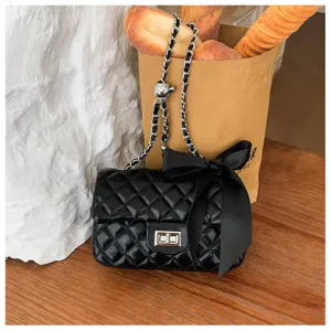 Chic black quilted chain crossbody bag with bow accent, elegant French style fashion handbag.