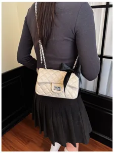 Quilted chain shoulder bag in off-white with black bow detail, elegant crossbody small square bag.