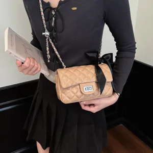 Elegant beige quilted chain crossbody bag with black bow accent and classic turn-lock closure.