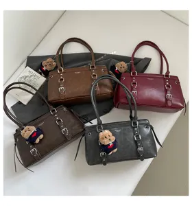 Details of the stylish shoulder bag featuring cute bear pendant and multiple buckle straps.