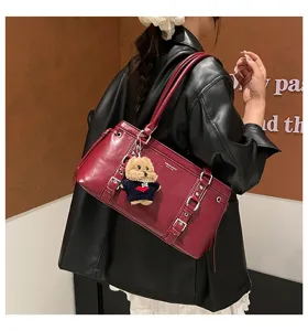 Wine red leather shoulder bag for women, stylish large tote with cute bear pendant and buckles.