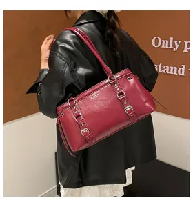 Wine red shoulder bag detail showing retro buckle strap and durable leather texture.