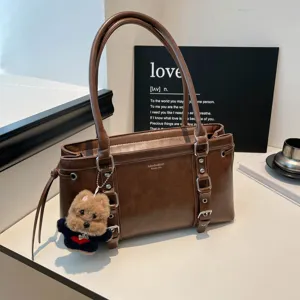 Brown leather shoulder bag with multi buckle details and cute puppy keychain for women daily commute.