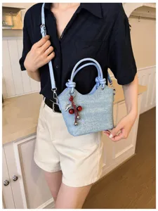 Close-up detail of a chic light blue bucket bag with cherry charm for daily commute style.