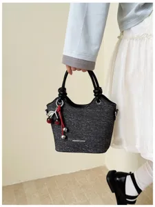 Detailed view of the dark grey textured bucket bag with black top handles and cute cherry charm.