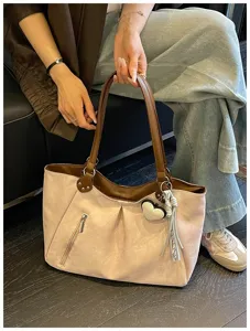 Detailed view of large pink tote bag with brown straps, front zipper pocket and cute charms.