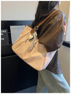 Close-up view of large shoulder tote bag with pink fabric, brown straps, and cute tassel.