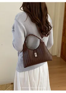 Detail view of dark brown woven shoulder bag worn by model, retro style minimalist accessory.
