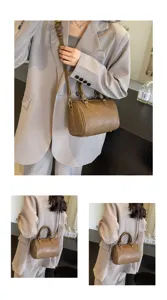 Detail view showing the stylish brown Boston bag worn crossbody and carried on shoulder.