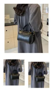 Detailed look at the black leather Boston pillow bag worn by a model in a daily casual outfit.