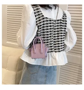 Detailed view of trendy purple snake-textured mini handbag with metal chain strap.