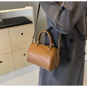Detailed shot of a brown women's PU leather Boston handbag worn crossbody, stylish and chic.