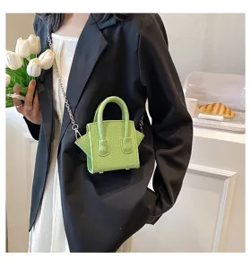 Green miniature top handle crossbody bag detail view, stylish textured design with metal chain.