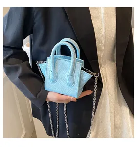 Closeup of mini light blue snake pattern handbag with silver chain strap and top handles.