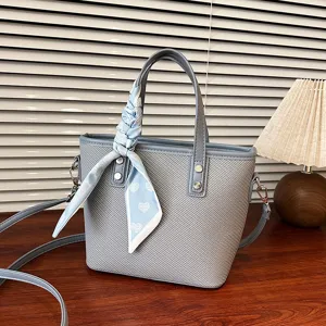 Stylish grey tote bag with blue scarf handle accessory, chic crossbody handbag for daily wear.