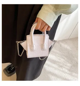 Close-up detail shot of a mini white textured handbag featuring metal chain and winged design.