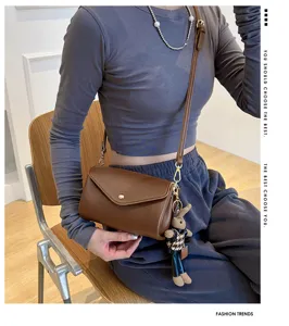 Women brown cylindrical crossbody bag stylish PU leather shoulder bag with cute rabbit charm.