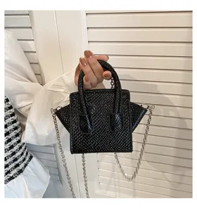 Detail shot of a trendy black textured mini handbag with top handles and chic chain strap.