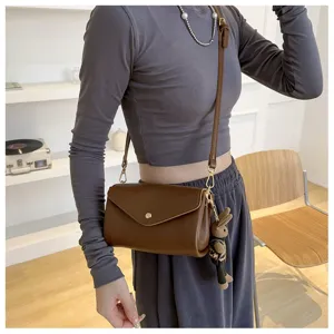 Detailed view of the stylish brown leather crossbody bag with cute rabbit pendant for women.