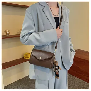 Brown leather crossbody bag with chic bear pendant, perfect daily accessory for women.