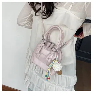 Detailed shot of a stylish pink retro women handbag with sweet ice cream charm and shoulder strap.
